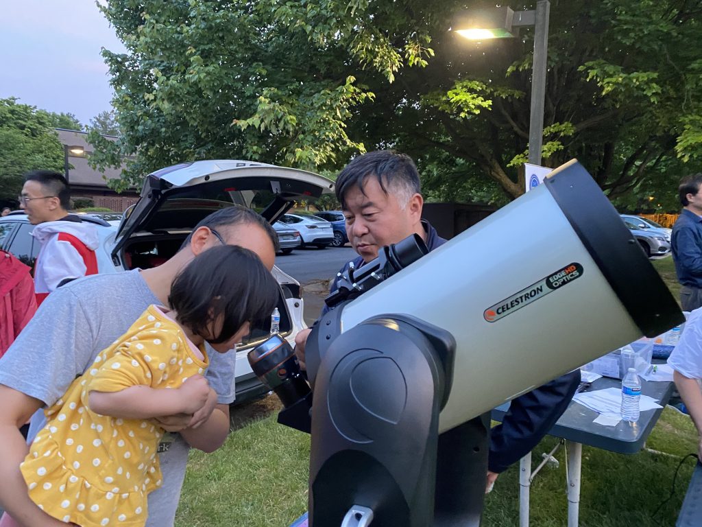 A parent and child observing Saturn through a telescope with guidance from Renjiang Xie