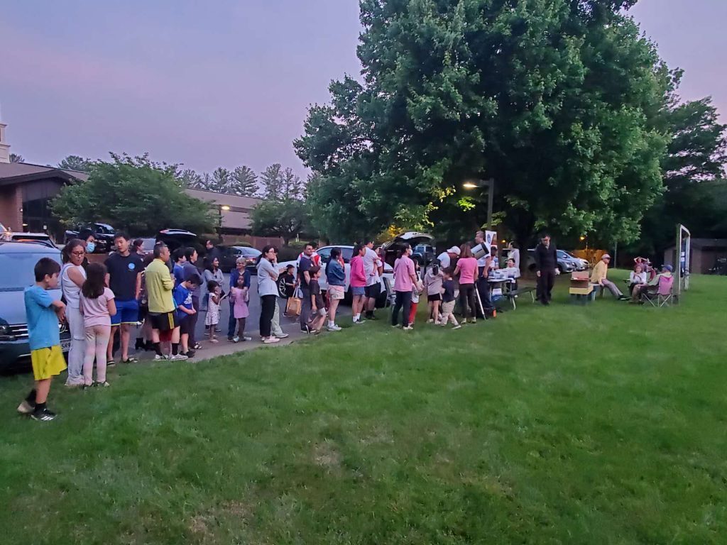 A crowd waiting in line to observe through a telescope