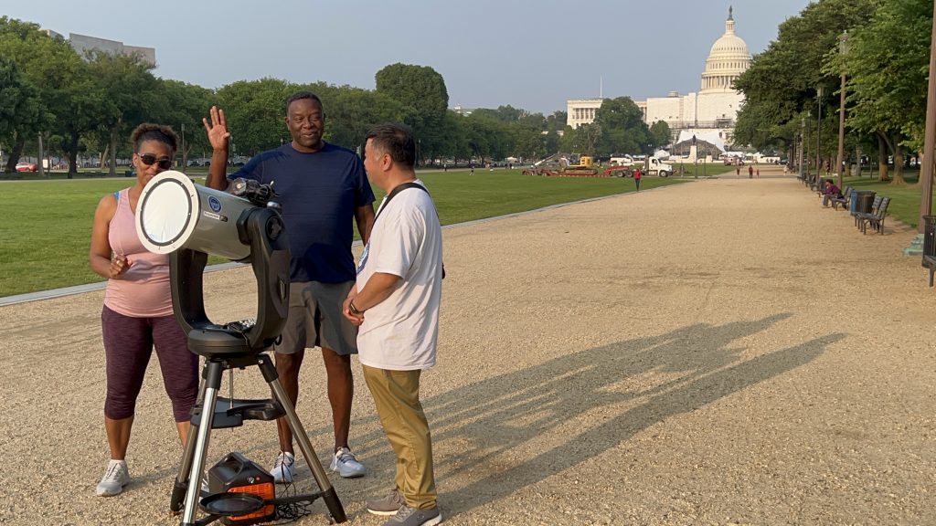Renjiang Xie explaining a telescope to visitors on the National Mall