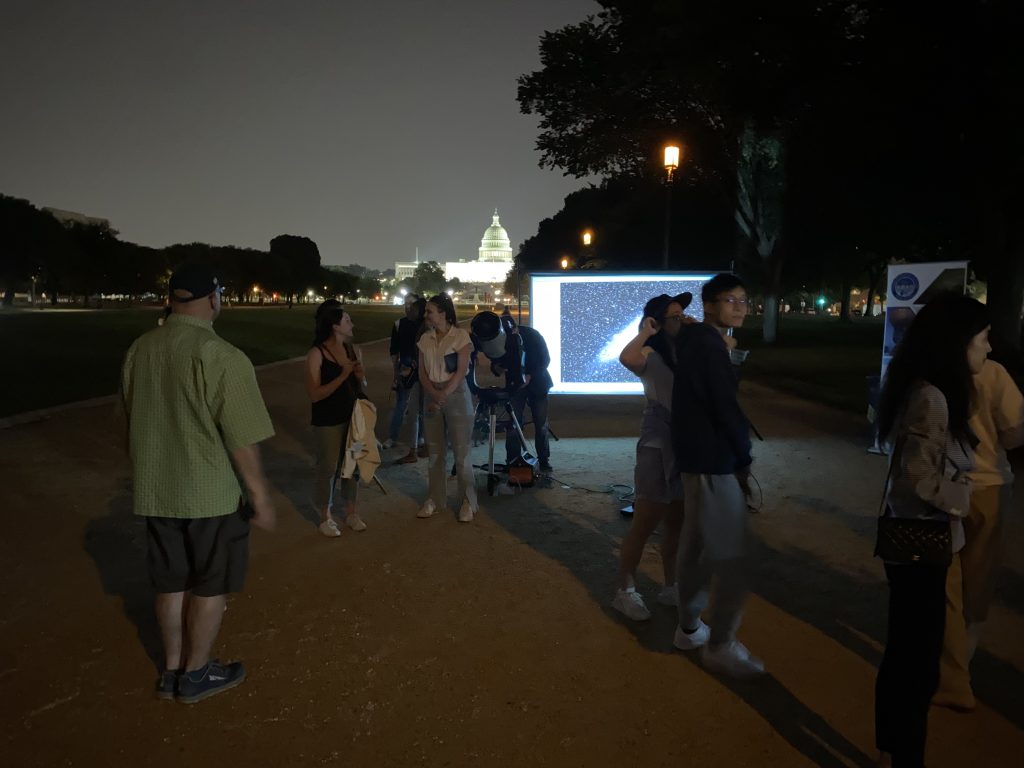 Passersby watching an astronomy projection on the National Mall