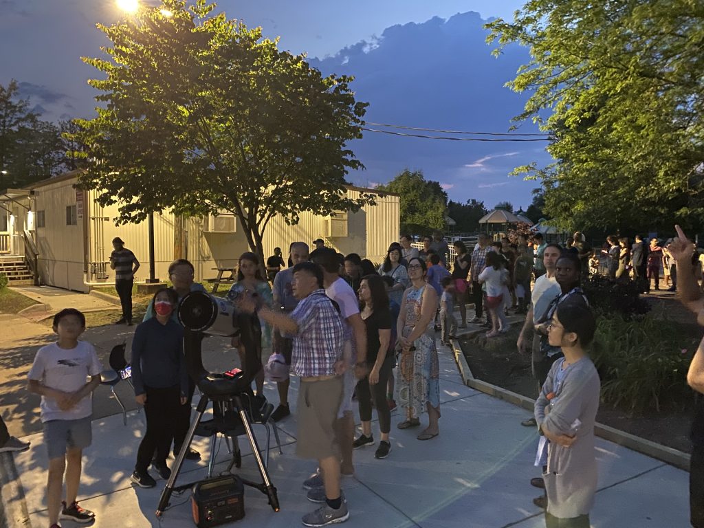 Renjiang Xie explaining Saturn observation to children and parents outdoors