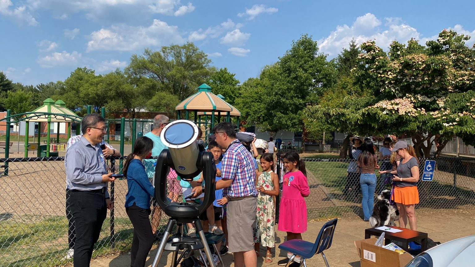 Children and ABAS volunteers gathering around a telescope during a school solar-observation program