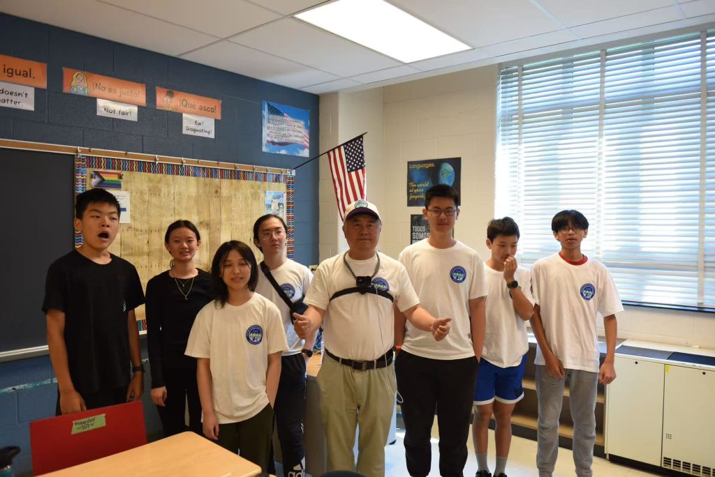 High school volunteers standing with Renjiang Xie in a classroom