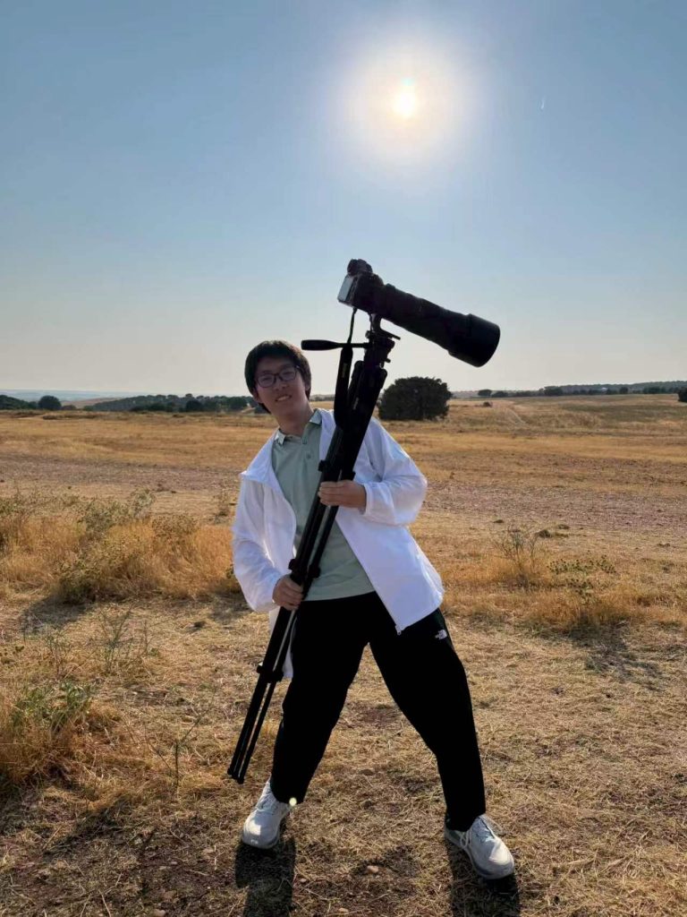 A team member in Lerma holding a tripod with a camera and telephoto lens