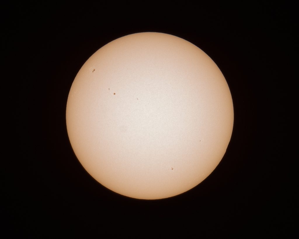 The solar disk photographed through a solar filter, showing groups of dark sunspots